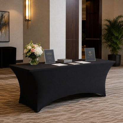 Black fitted spandex banquet table cover displayed in a professional hotel or event venue setup, ideal for registration, catering and trade show tables.